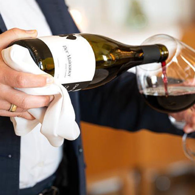 Eine Person gießt Rotwein in ein Weinglas